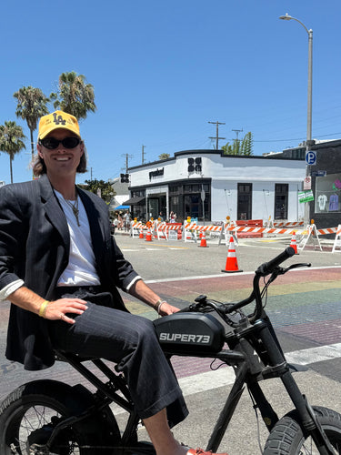 Matthew on an electric bike wearing a Good Quality Human hat