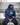 A man wearing a navy blue hoodie with 'GOOD QUALITY HUMAN' printed on the chest, sitting outdoors in front of a blurred city and waterfall background. The post is from Ice Cube on Instagram.